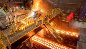 Manschen in Schutzanzügen in einer Stahlfabrik