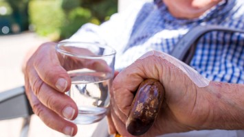 Senior mit Wasserglas und Gehhilfe