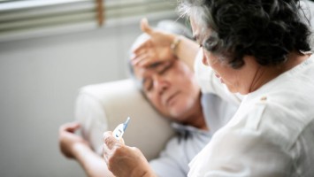 Einem Mann wird Fieber gemessen