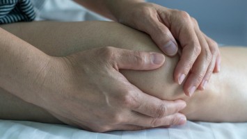 Frau unkenntlich fasst sich ans Knie