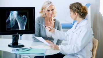 Teaserbild Ärztin mit Patientin im Gespräch vor Bildschirm