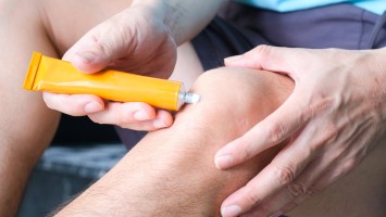 Mann appliziert Salbe auf sein Knie