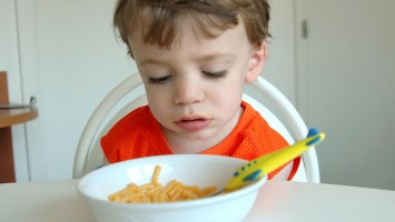 Unglücklich anmutendes Kind beim Nudelessen