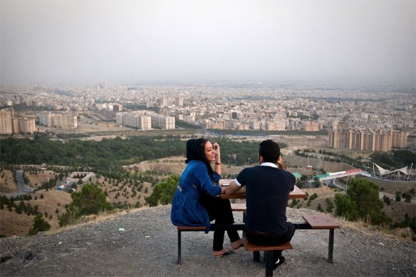 Ein Paar sitzt auf einem Hügel über der iranischen Hauptstadt Teheran