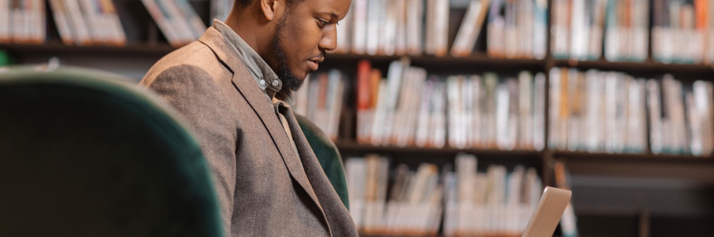 A male scientist is sat in a chair looking at his laptop