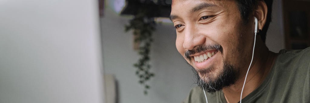 Young, smiling man uses desktop computer