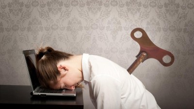 Mitarbeiterin stützt vor Erschöpfung ihren Kopf auf dem Laptop ab 