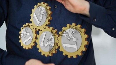 Zahnräder aus Ein-Euro-Münzen wird von Händen umrandet.