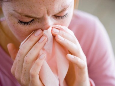 Junge Frau putzt sich die Nase mit Taschentuch