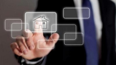 Ein Mann tippt mit dem Finger auf ein elektronisches Symbol mit einem Haus 