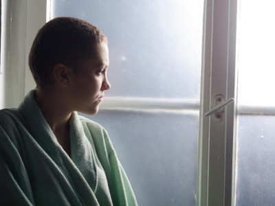 Eine junge Krebspatientin schaut aus dem Fenster