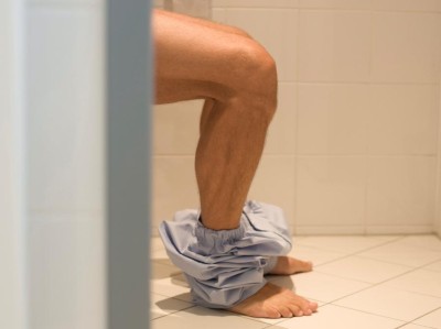 Mann sitzt auf Toilette