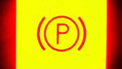 Ein Zeichen für Handbremse leuchtet rot auf gelbem Grund auf mit einem "P"