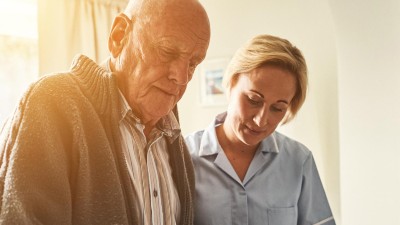 Pflegerin stützt älteren Patienten