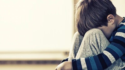Junge mit Kopf zwischen den Knien