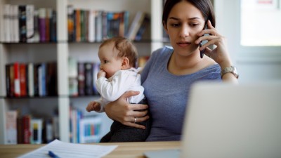 Frau am Telefon mit Baby auf dem Arm