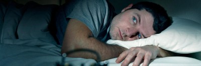 Mann liegt wach im Bett