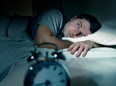 Mann liegt wach im Bett