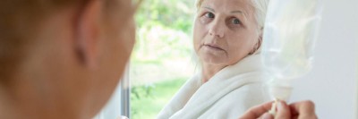 Patientin schaut besorgt auf Infusionsbeutel