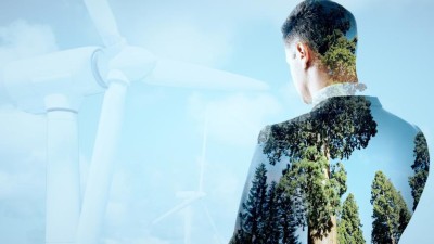 Geschäftsmann steht vor Windrädern