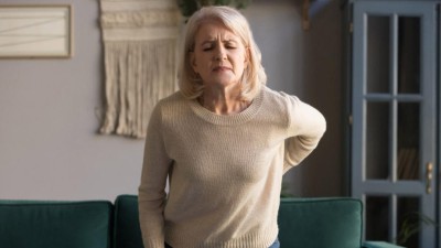 Frau mit schmerzverzerrtem Gesicht in Wohnzimmer