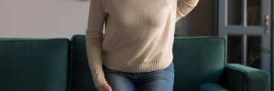 Frau mit schmerzverzerrtem Gesicht in Wohnzimmer