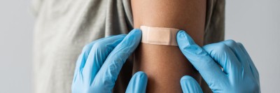 Person klebt Pflaster auf einen Arm