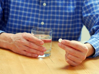 Mann hält Tablette und ein Glas Wasser in den Händen
