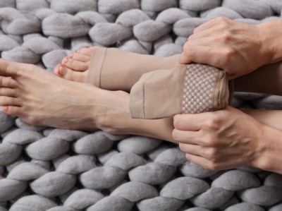 Eine Frau zeiht Kompressionstrümpfe auf dem Teppich an