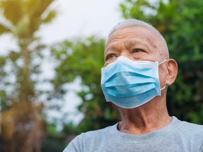Ein älterer Mann steht mit Maske im Garten