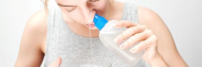 Eine Frau spült ihre Nase mit einer Kochsalzlösung