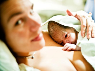 Neugeborenes liegt auf der Brust der Mutter