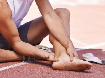 Läufer umfasst sein Sprunggelenk