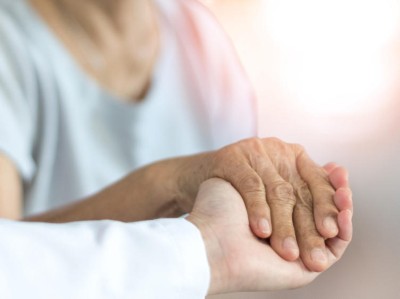 Einer älteren Person wird die Hand gehalten