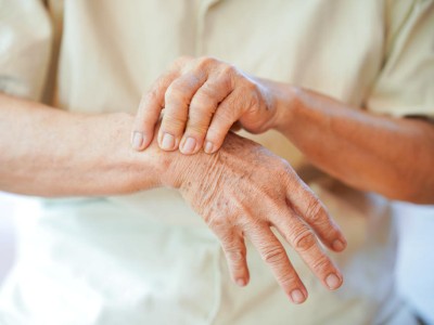Eine ältere Person fasst an ihr Handgelenk