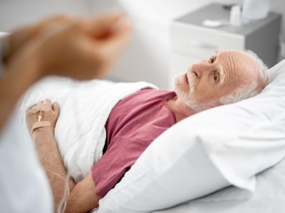 Alter Mann liegt im Krankenbett und bekommt Infusion