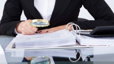 Frau mit Lupe sucht in Akten