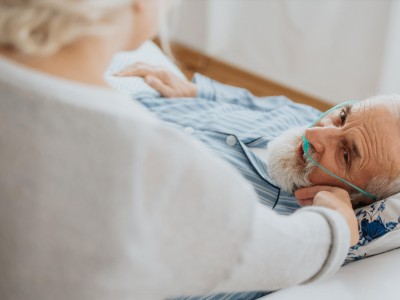 Ältere Frau unterstützt ihren sterbenden Mann im Krankenhausbett