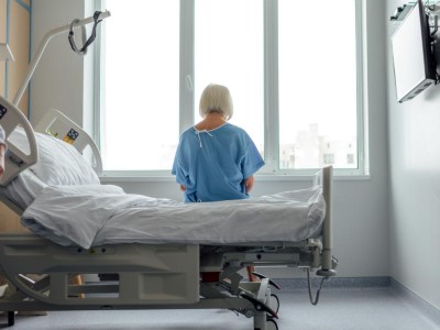 Ältere Patientin sitzt auf Krankenhausbett