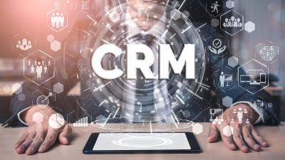 Zwei Hände liegen neben einem Laptop unter der Aufschrift CRM