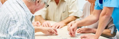 Fachperson betreut Senioren beim Puzzlen