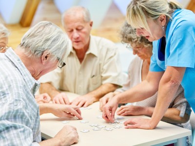 Fachperson betreut Senioren beim Puzzlen