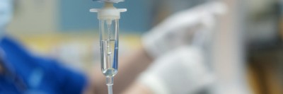 Infusionstropf mit Pflegepersonal im Hintergrund