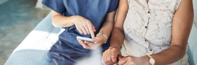 Pflegerin erklärt Patienten etwas auf dem Smartphone