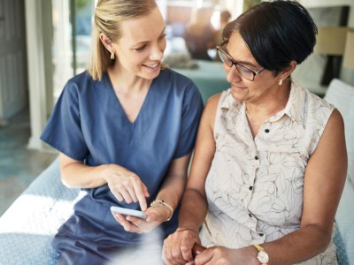 Pflegerin erklärt Patienten etwas auf dem Smartphone