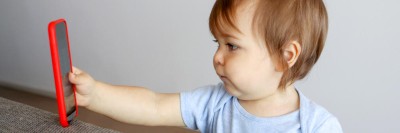 Kleinkind starrt auf Bildschirm eines Smartphones
