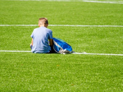 Junge allein auf Sportplatz sitzend