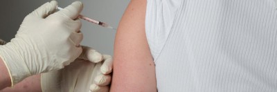 Person injiziert Medikament in den Arm einer Patientin