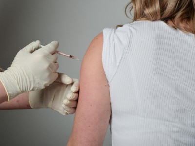 Person injiziert Medikament in den Arm einer Patientin