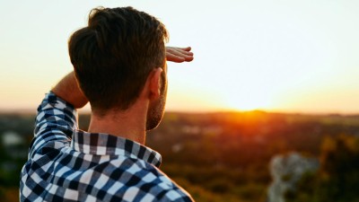 A man looks at a sunset in the distance